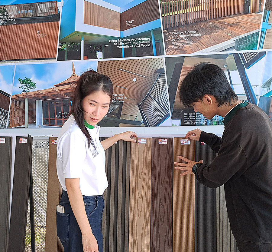 พนักงาน SCi Wood แนะนำสีไม้ผนังและไม้ระแนง WPC ให้ลูกค้าหน้าผนังตัวอย่างงานจริง