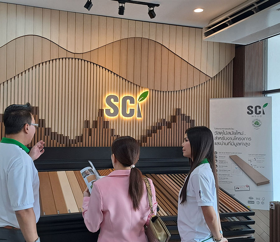 ทีมงานแนะนำไม้สังเคราะห์ SCi Wood ให้ลูกค้าหน้าผนังโลโก้ SCi ในโชว์รูม IDM Premium Outlet