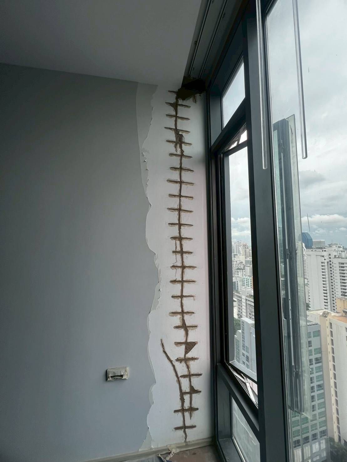 เย็บรอยร้าวผนังข้างหน้าต่างด้วยเหล็กเย็บ วิวเมืองกรุงเทพ