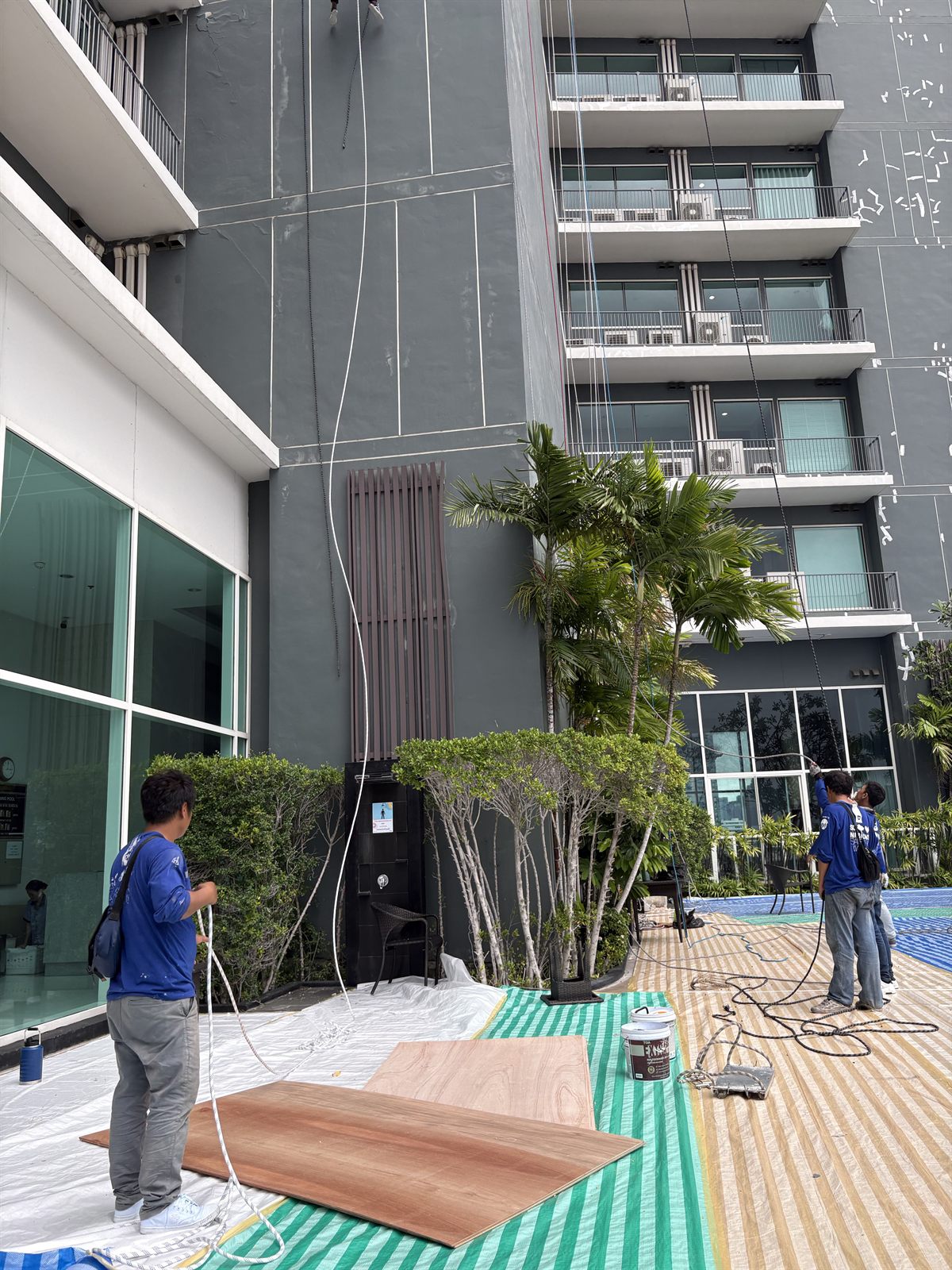 ปูผ้าใบและแผ่นไม้ป้องกันพื้นและสระว่ายน้ำโรงแรม ระหว่างงานซ่อมผนังภายนอก